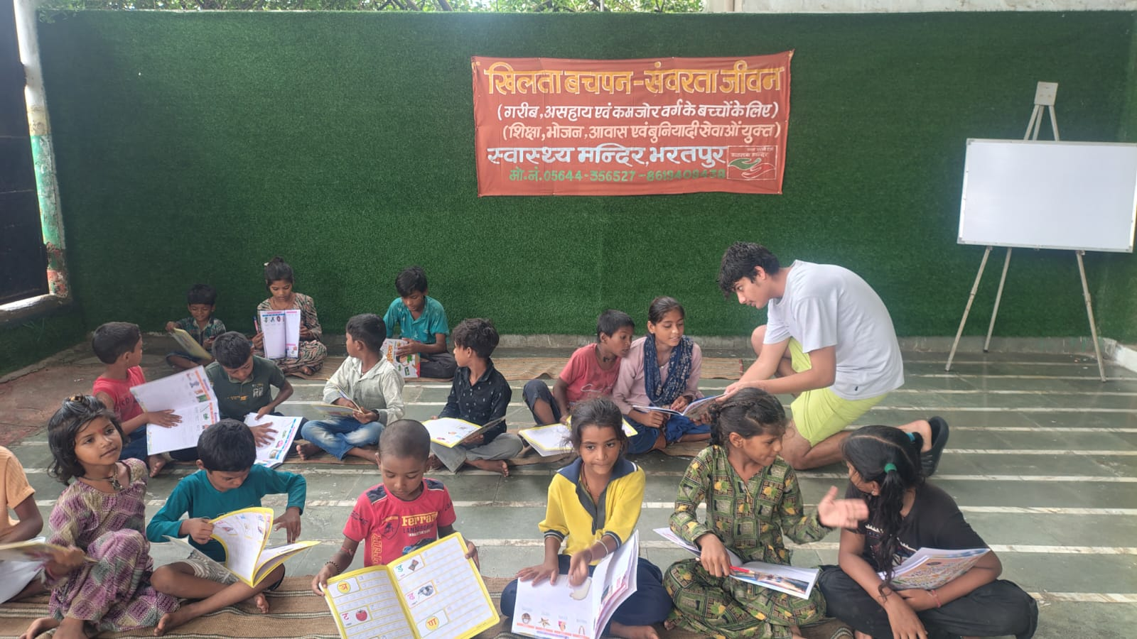 The full group of children sitting together with new books
